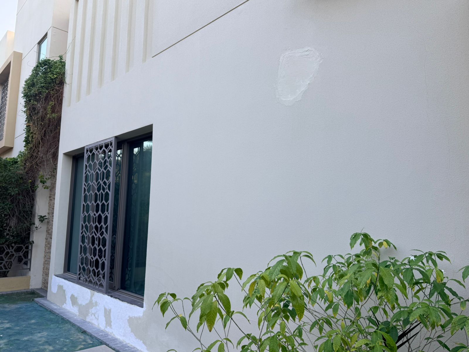 Facade wall before final blend coat, showing patched repair area
