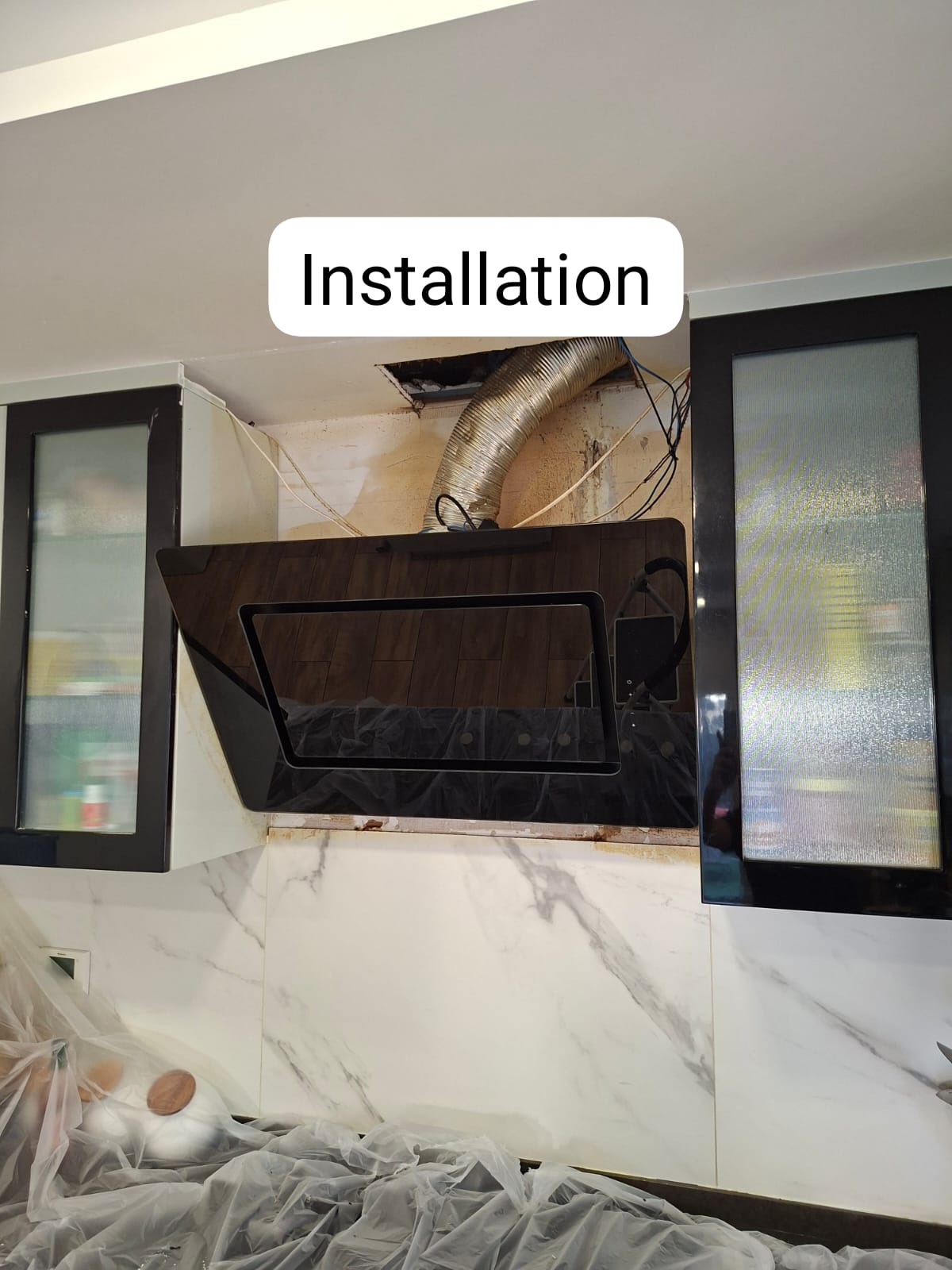 New angled black glass hood being mounted & ducted