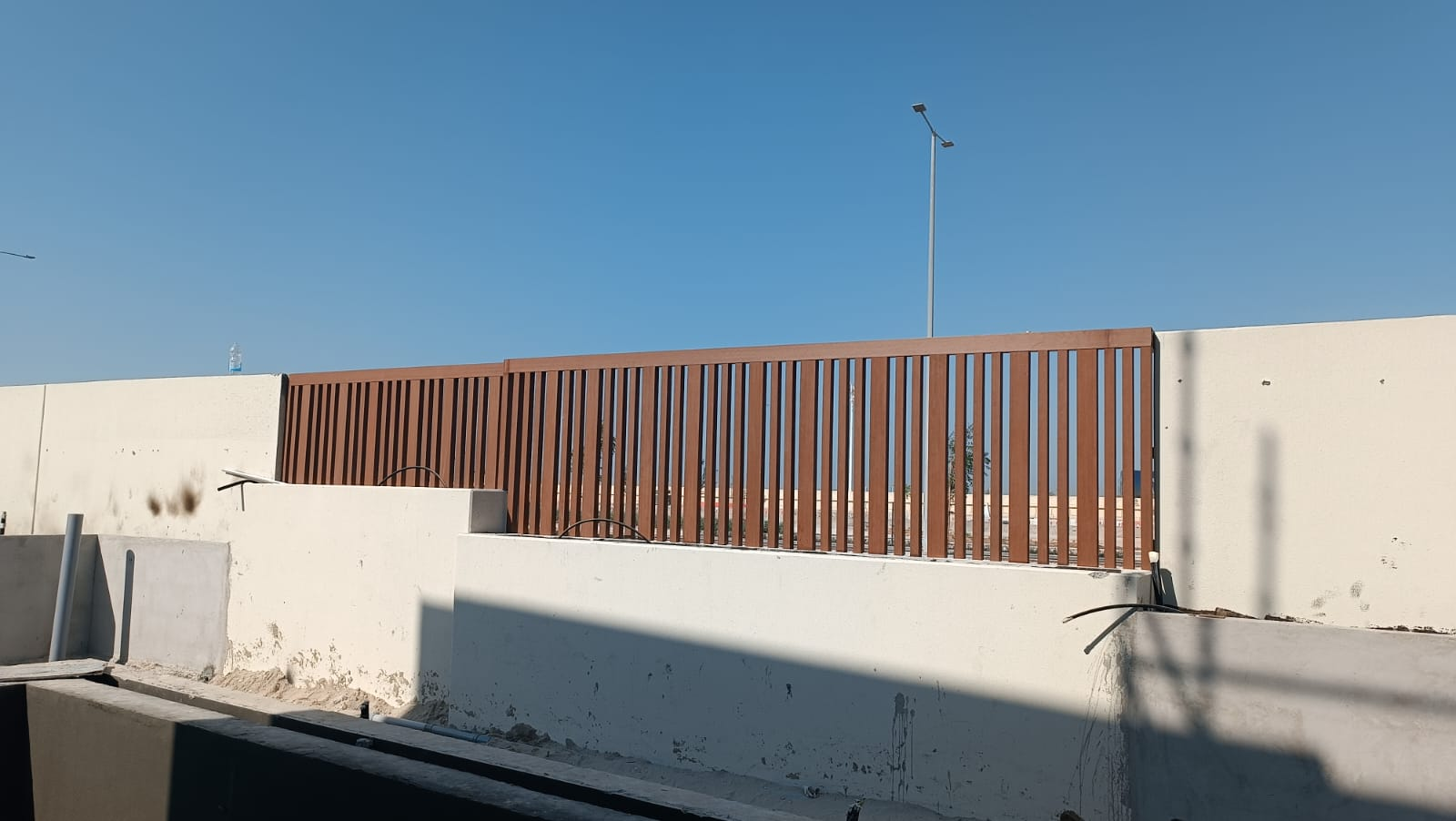 Freshly stained timber-slat fence on top of the boundary wall