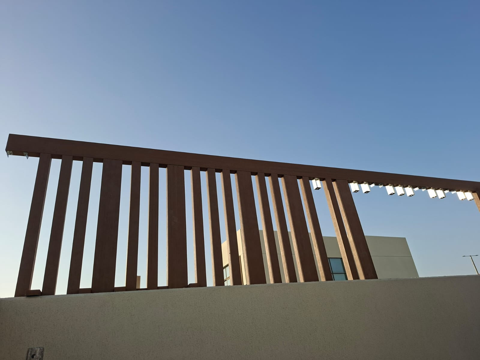 Completed slatted timber-look pergola screen crowning the rooftop terrace wall