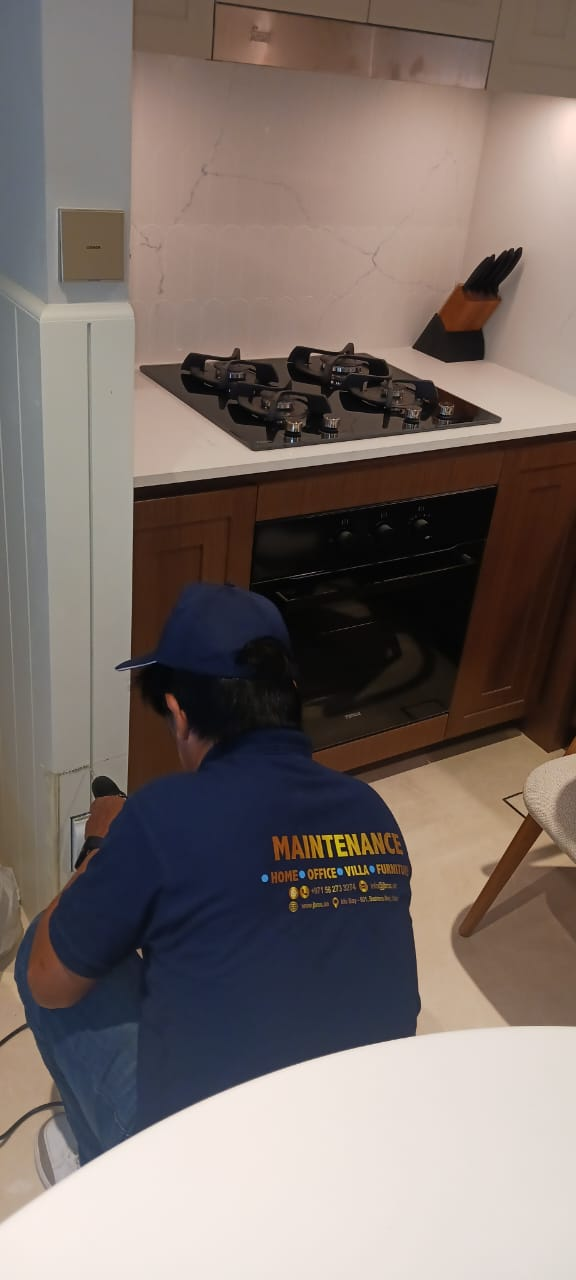 Technician servicing a built-in gas hob and oven unit