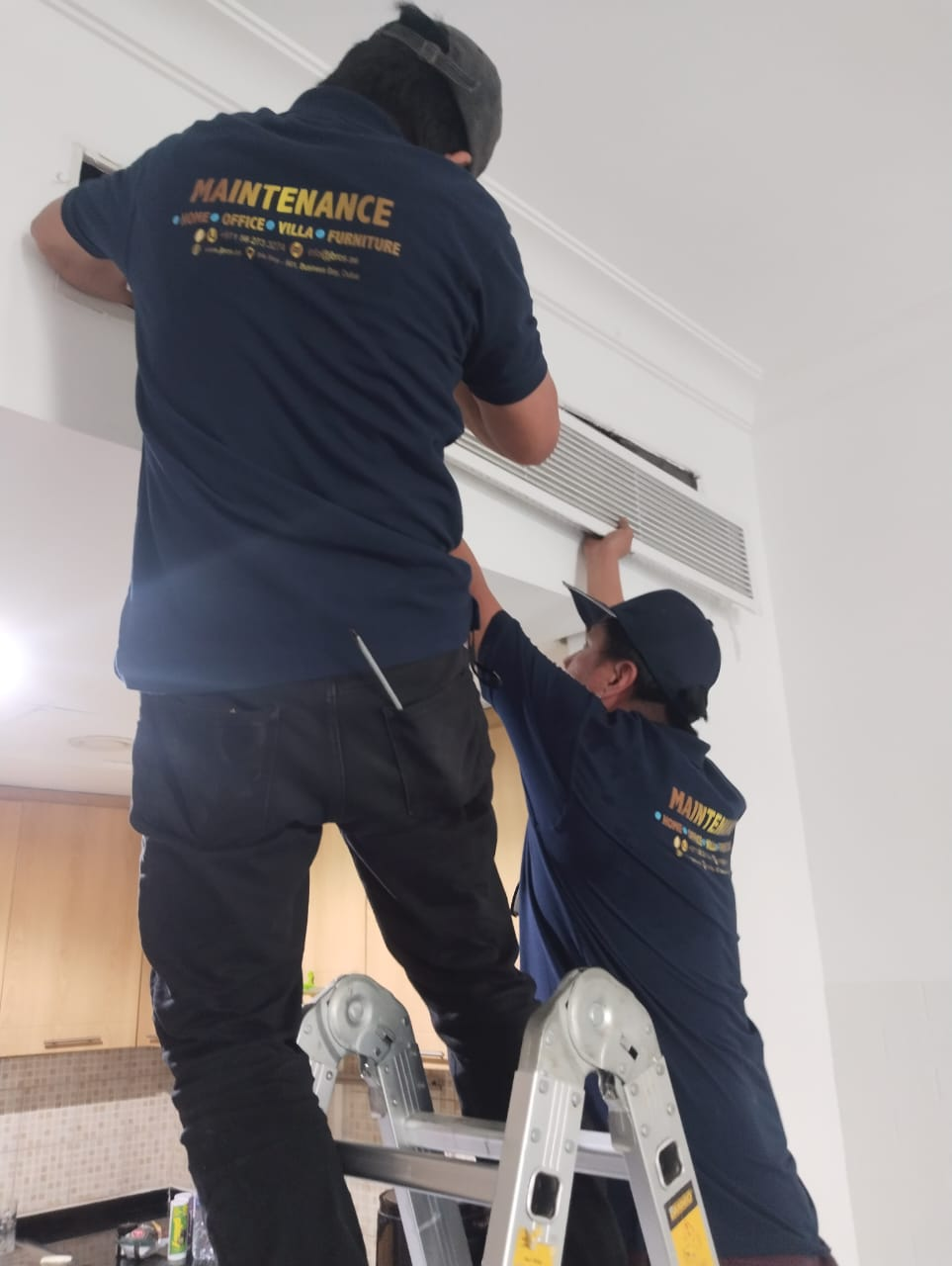 Two-technician team refitting a ducted AC vent after servicing
