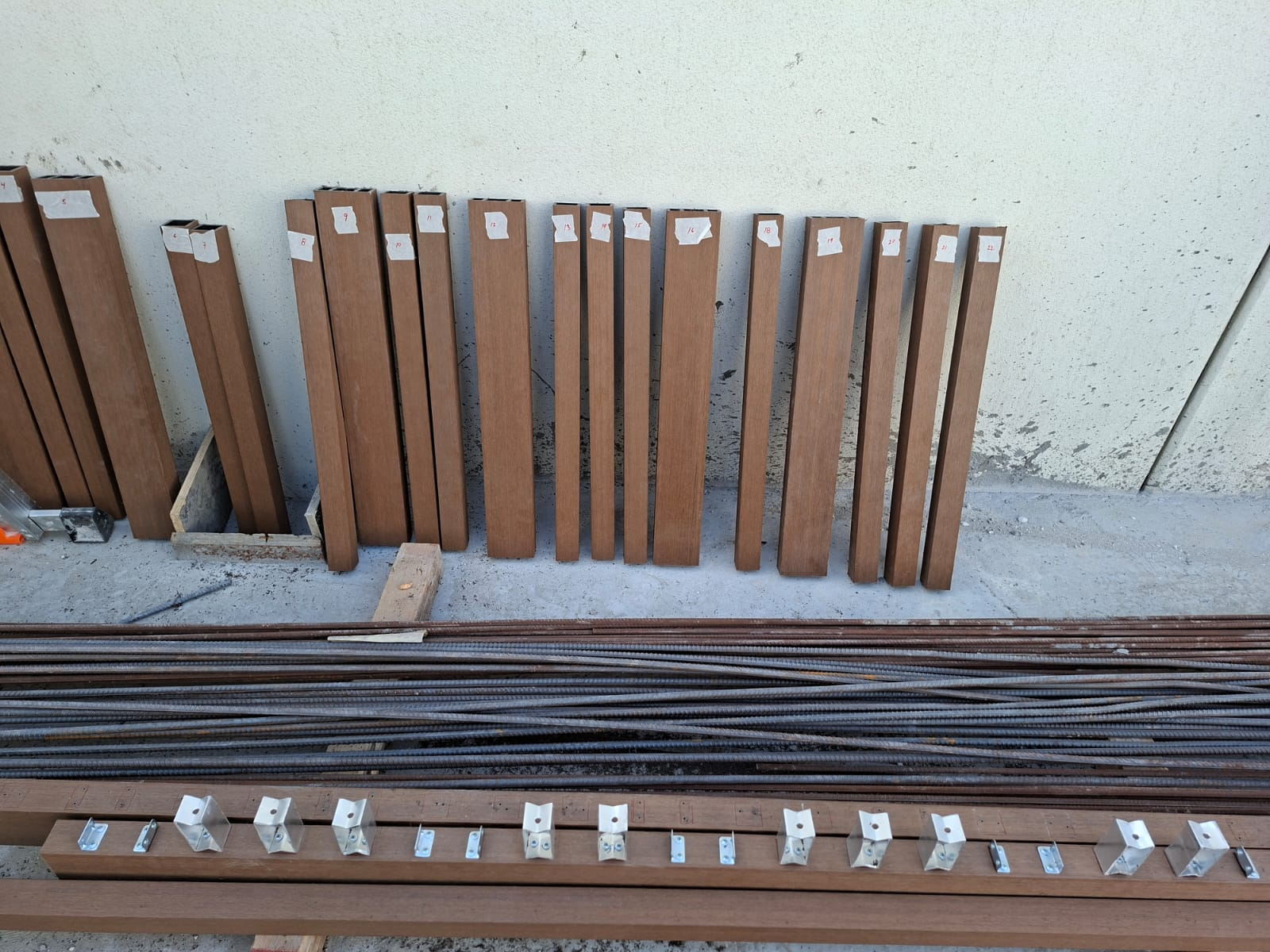 Numbered composite slats and steel rebar laid out ready for pergola assembly