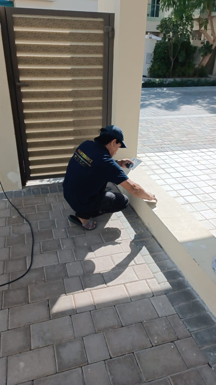 Detail patching and edge repair along the driveway plinth and wall base